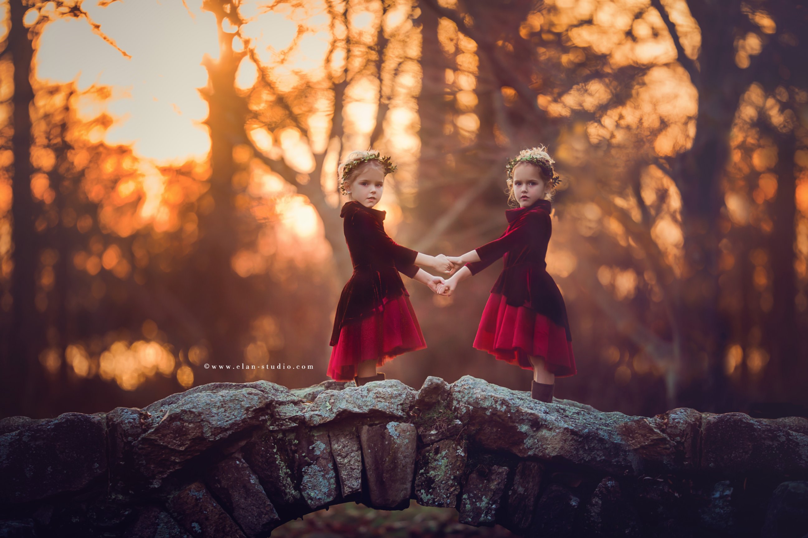 twin girls wearing matching cranberry colored dresses against natural autumn background