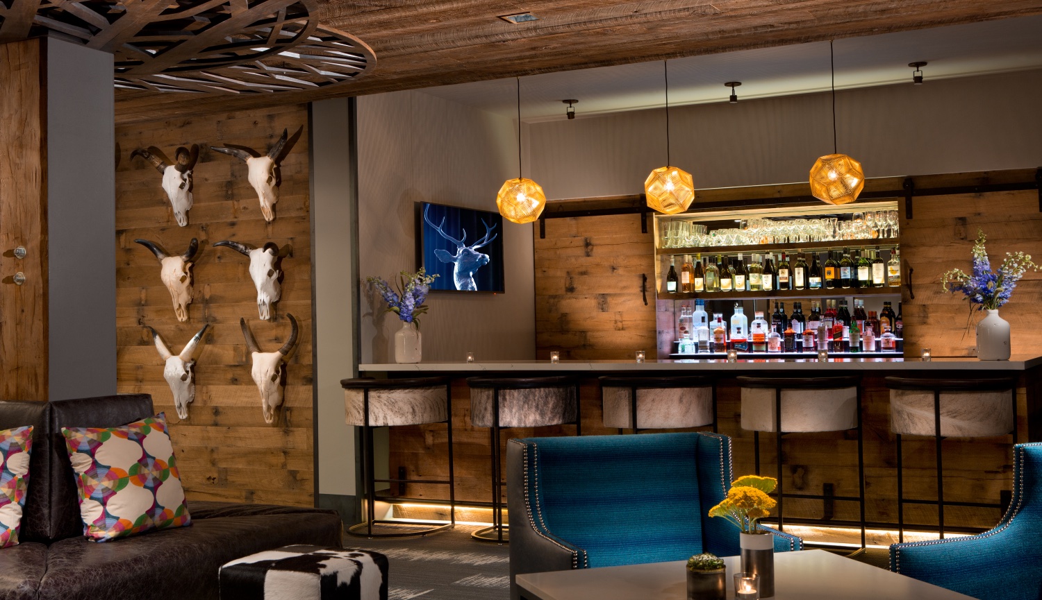 Hotel Lobby in Jackson Hole Wyoming decorated to look more like a modern saloon with cow heads on wall and beautifully lit bar.