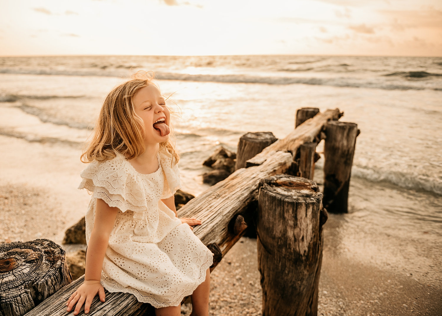 silly little girl sitting on beach pilings, Naples Beach, Florida, Ryaphotos