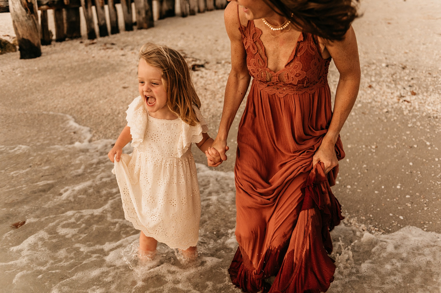 mother and daughter holding hands and running into Florida beach surf, Ryaphotos