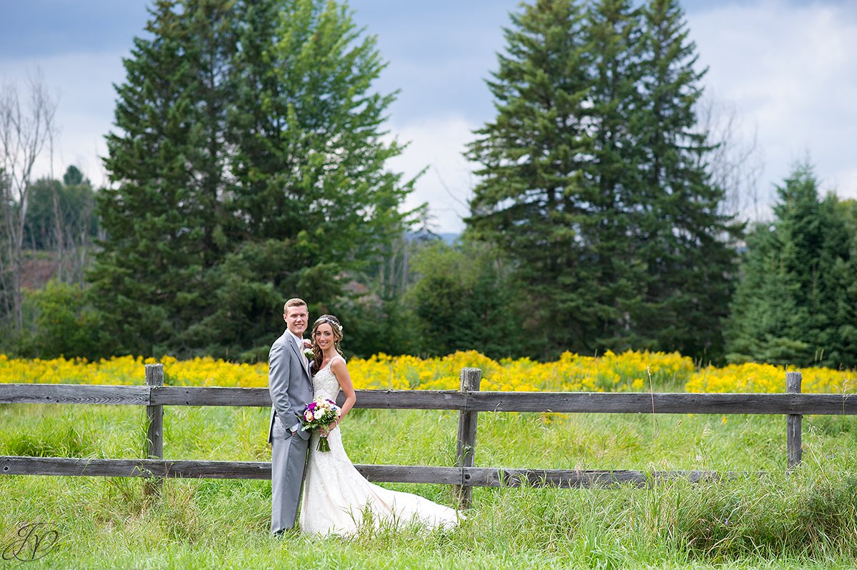 bride and groom near fence lake placid yellow flowers
