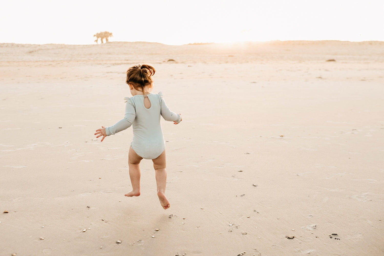 toddler girl jumping in the sand on the beach, Florida, Ryaphotos