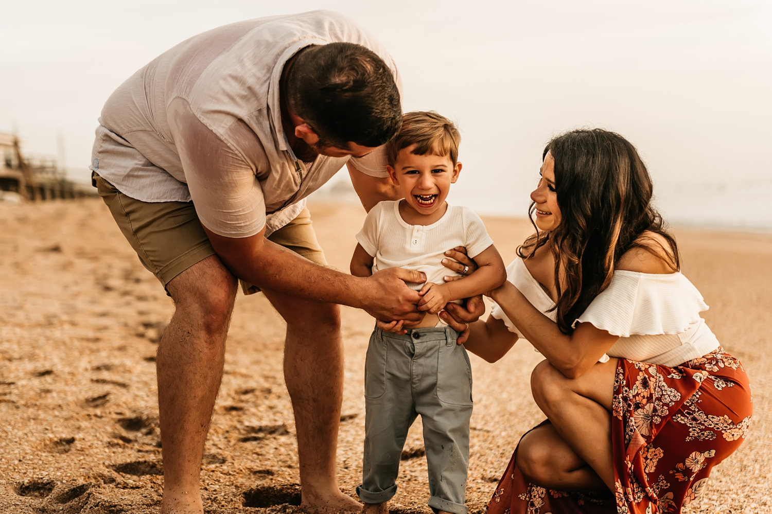 mother and father tickling toddler son on the beach at sunrise, Rya Duncklee Photos