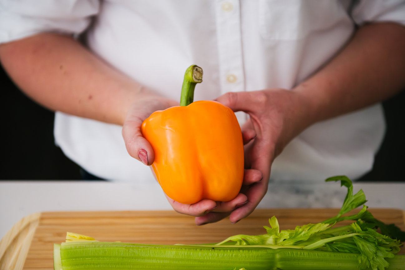 detail shot of entrepreneur dietitian holding yellow pepper in kitchen during brand session