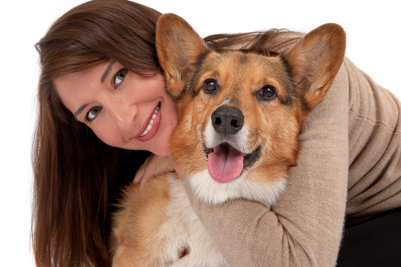 Woman hugging a happy corgi dog