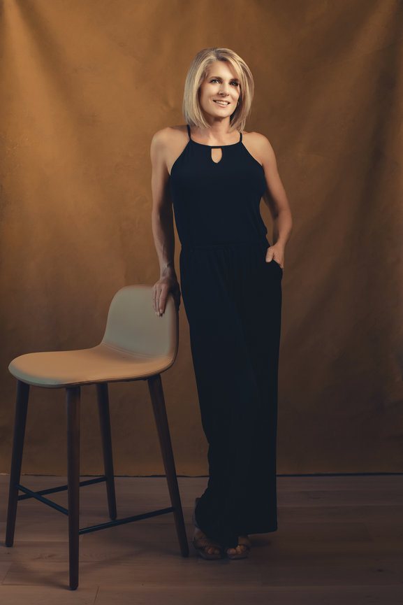 Woman in black jumper standing in photography studio with hand painted golden yellow backdrop, taken in a photo studio with Adam Trujillo, a Las Vegas portrait photographer.