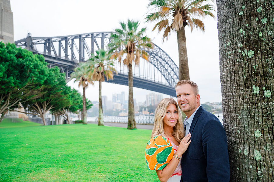 A photoshoot with a couple standing in front of the Sydney Harbour bridge.