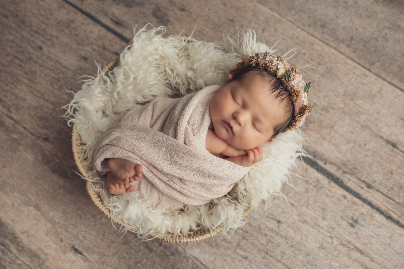 Sleeping baby in a fluffy basket with headband