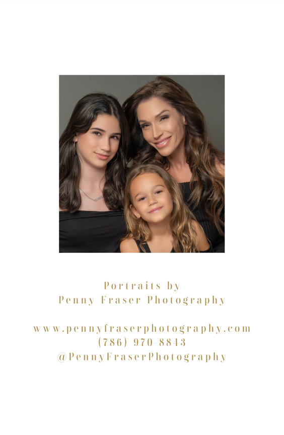 Group portrait of mother and two daughters smiling close together.
