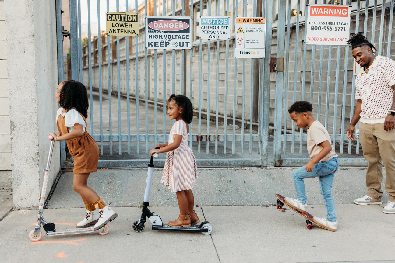 Huntsville Alabama photoshoot Black family ride scooters down city sidewalk