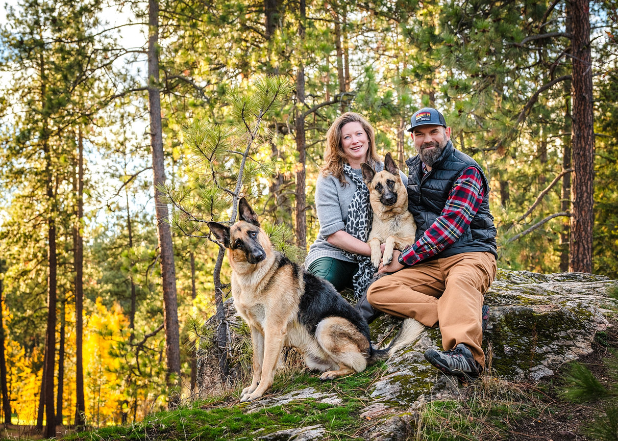 Couple with two dogs in Post Falls park, finished portrait with clean background and no visible leash.