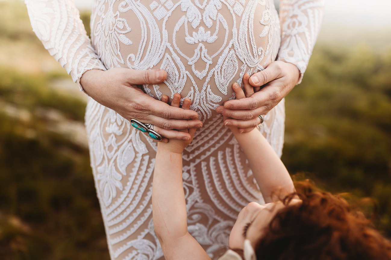 A girl's hands on her mother's belly during a maternity photography session in New Jersey.