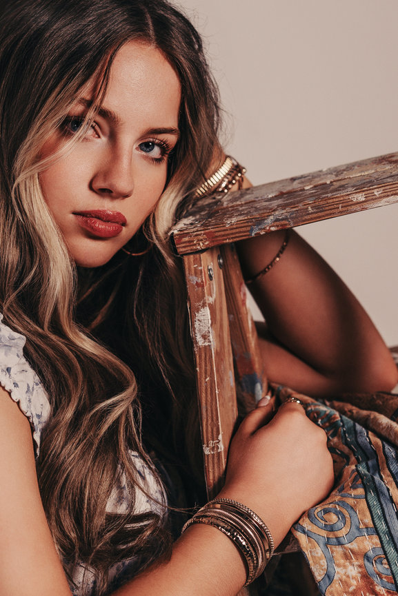 Close-up portrait of a woman leaning on a wooden beam.