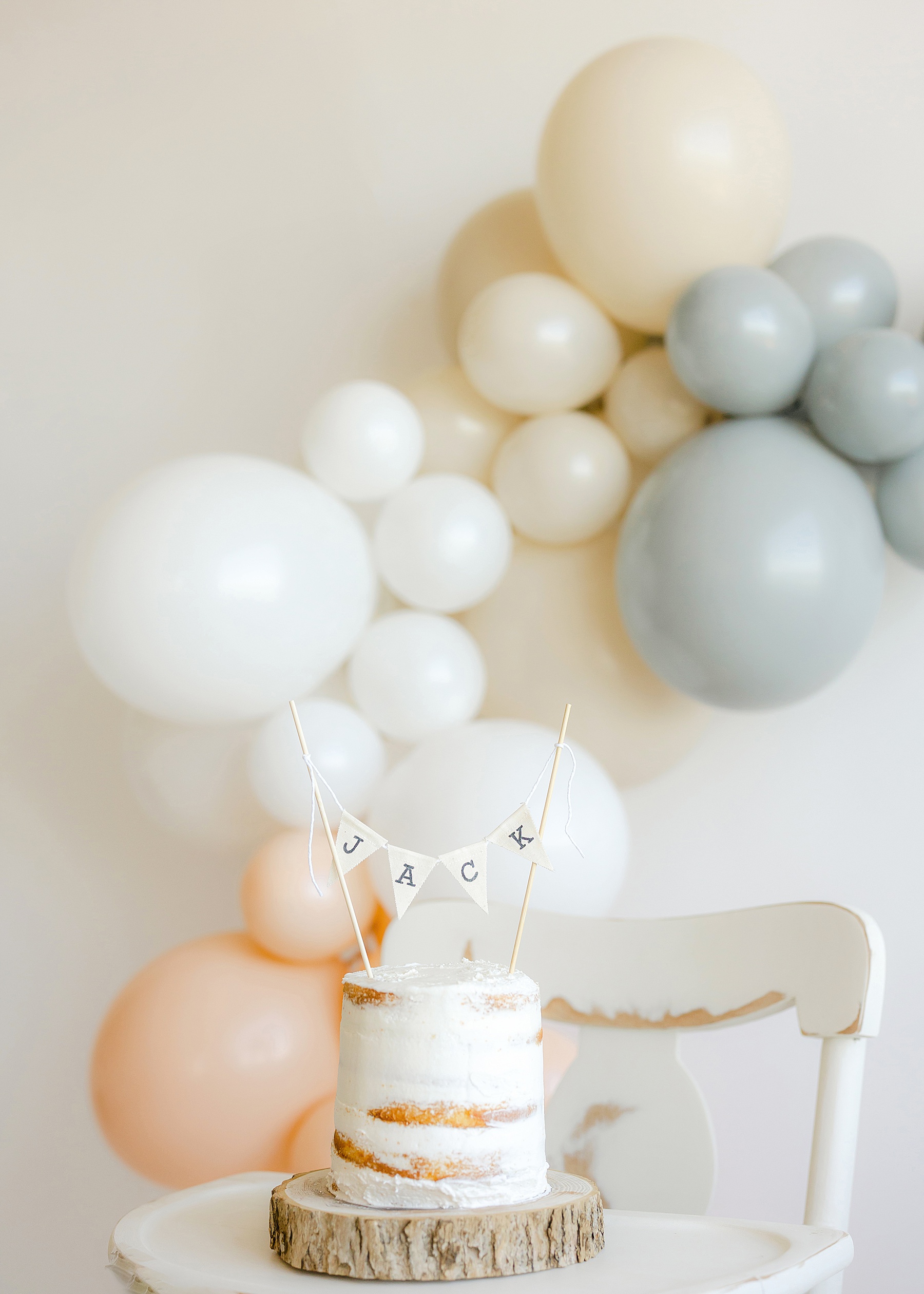 white smash cake first birthday photo with balloons on white background