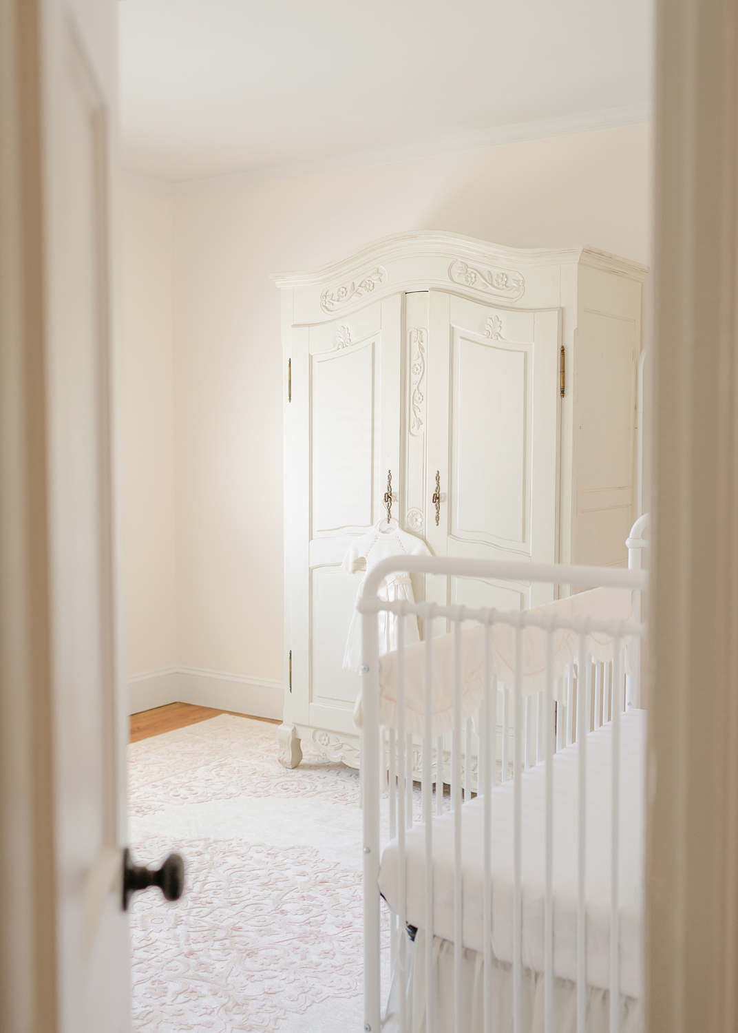 all white nursery with white hutch and pink and white rug for newborn