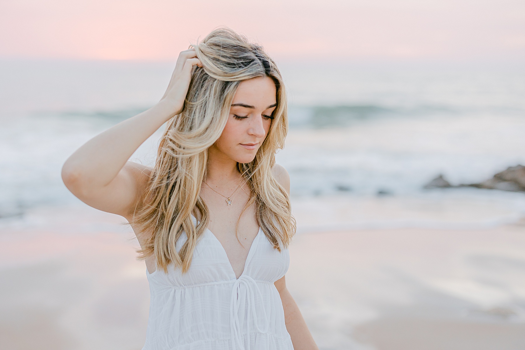 light and airy pastel skies on the beach behind a young woman in a white dress