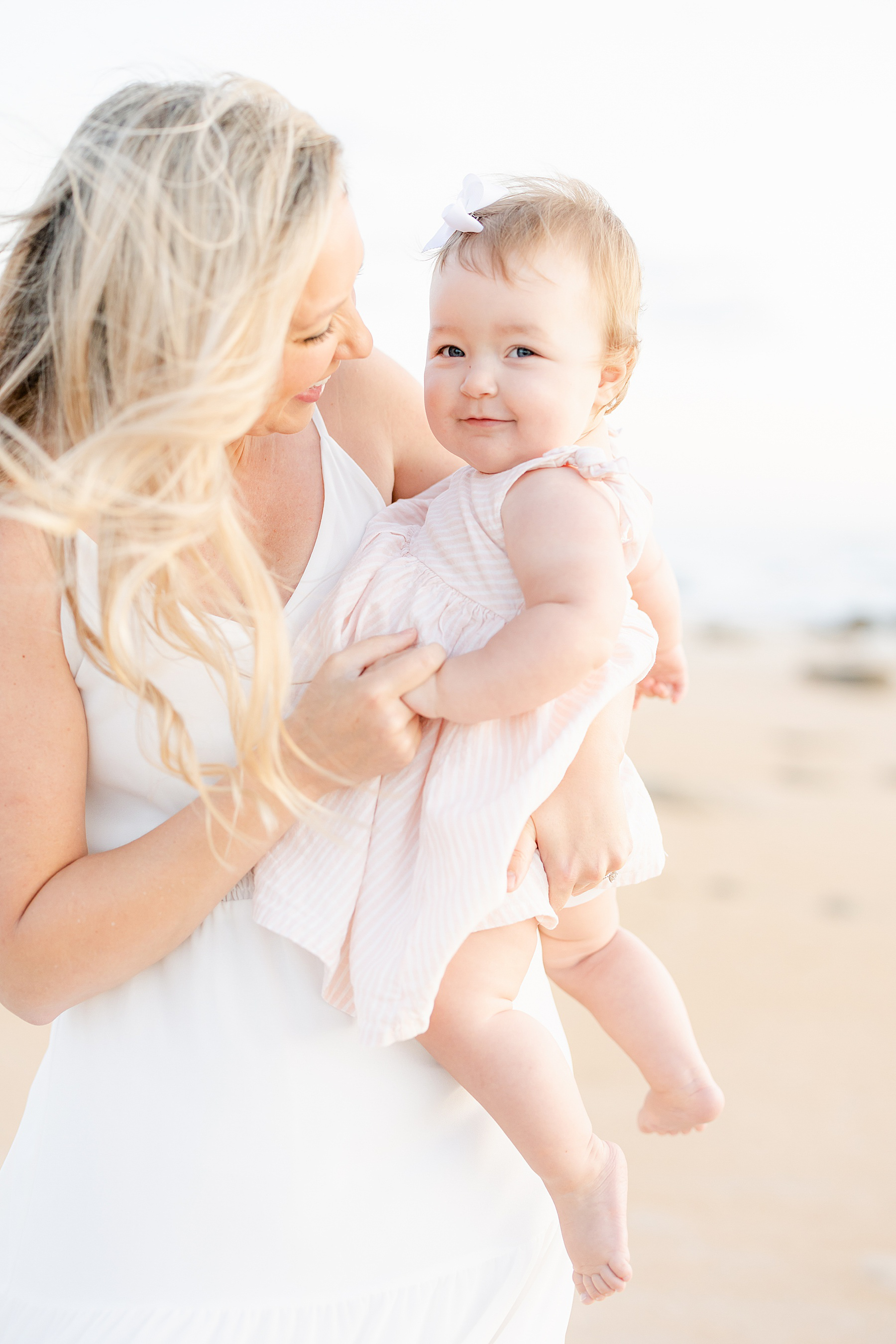 baby girl pink striped dress sunrise beach photo woman with blonde hair holding baby girl