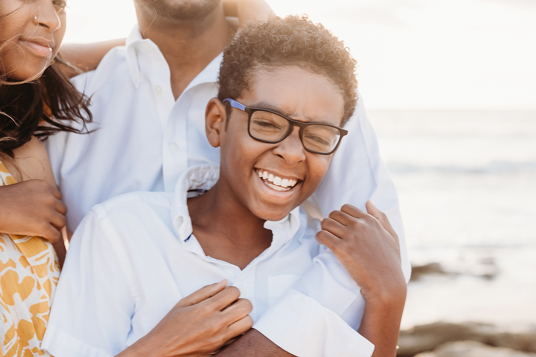black boy in white shirt with blue rimmed glasses laughing