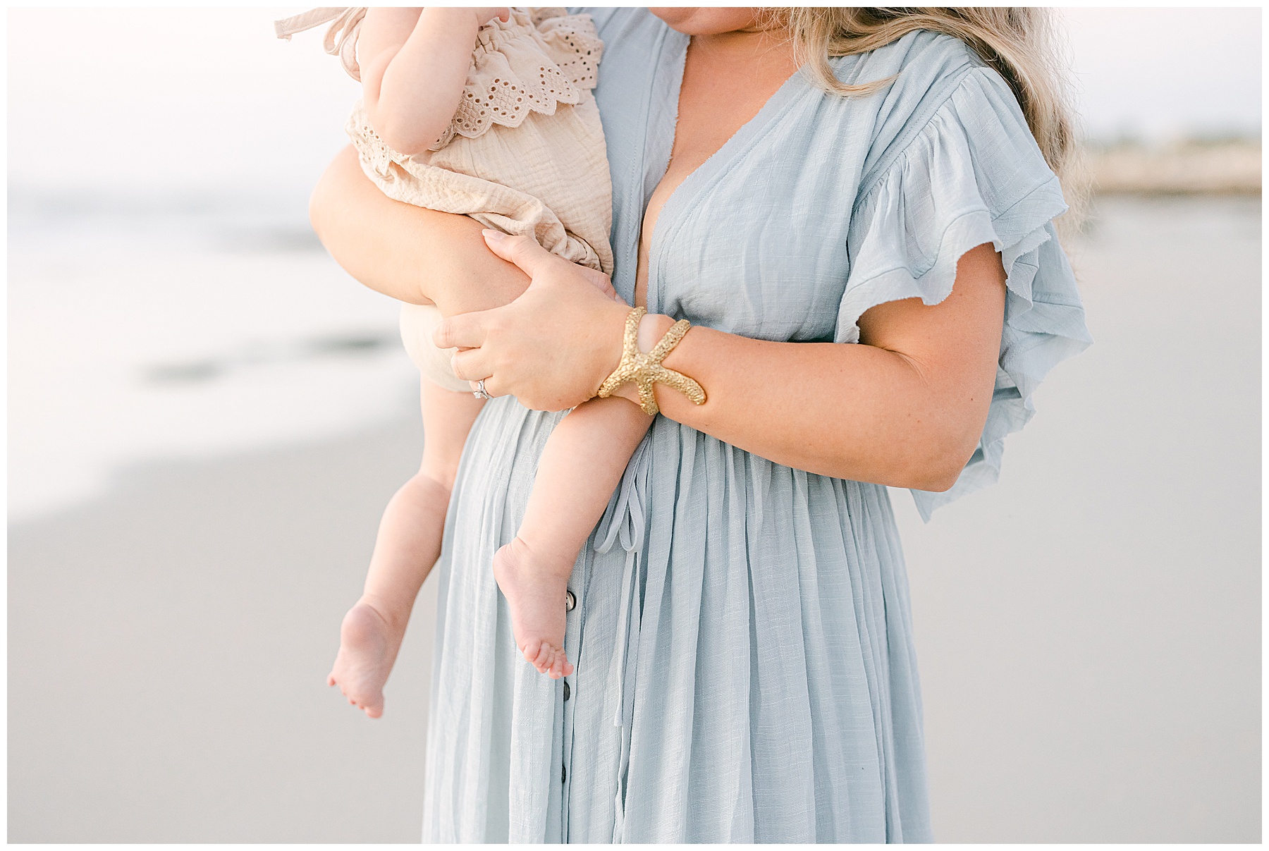 close up of woman holding baby girl wearing gold starfish bracelet
