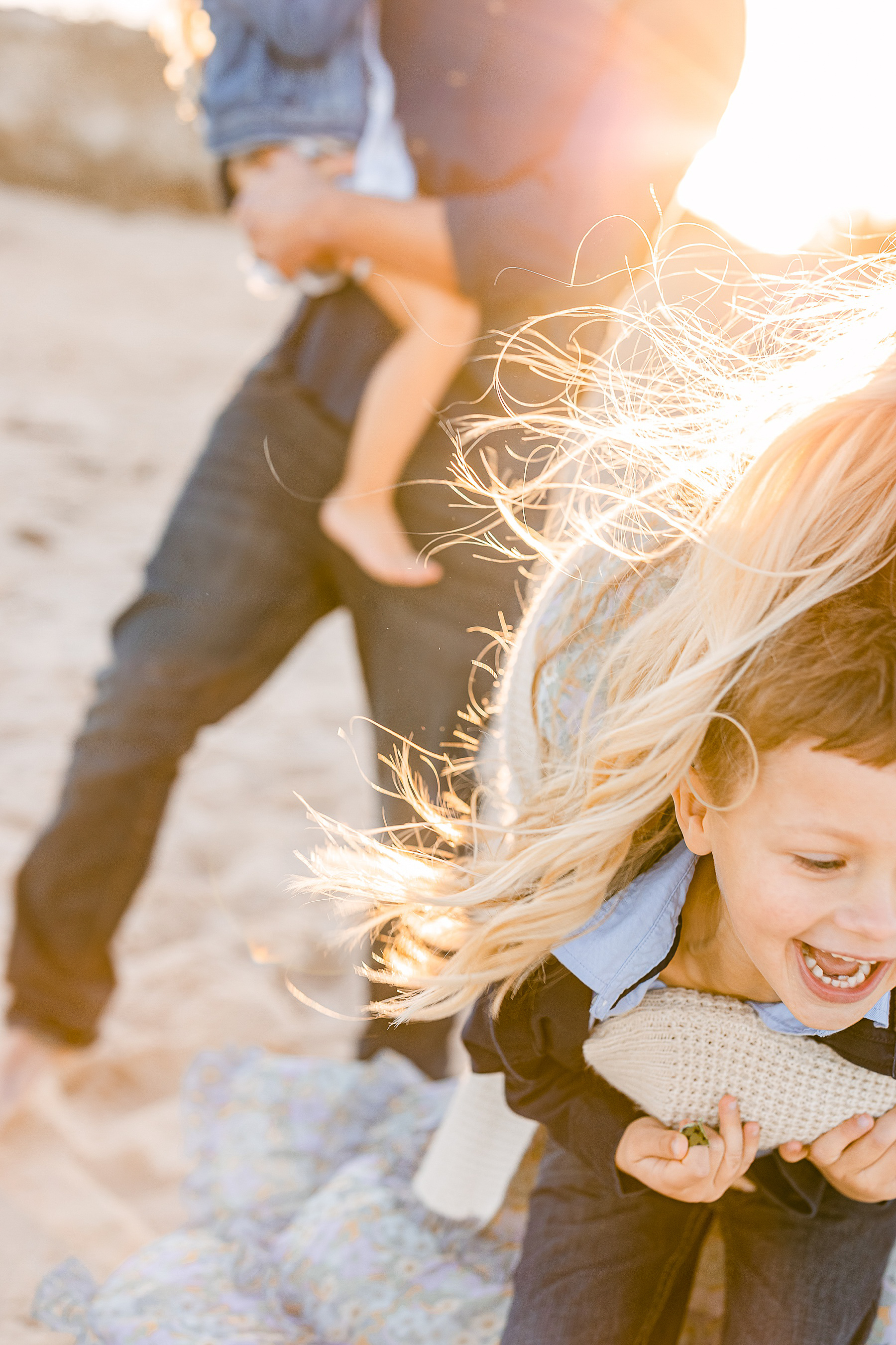 backlit sun haze photo of blond women's hair on the beach playing with children