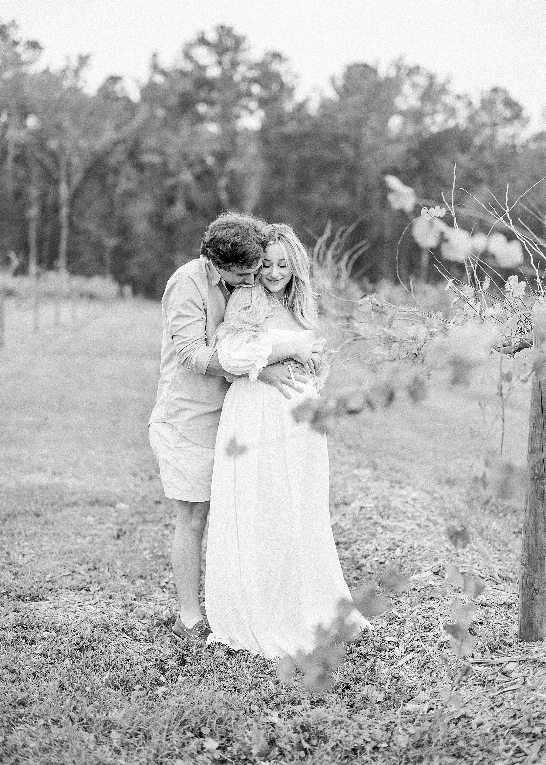 black and white maternity portrait of couple holding each other in the vineyards at Congaree and Penn farm
