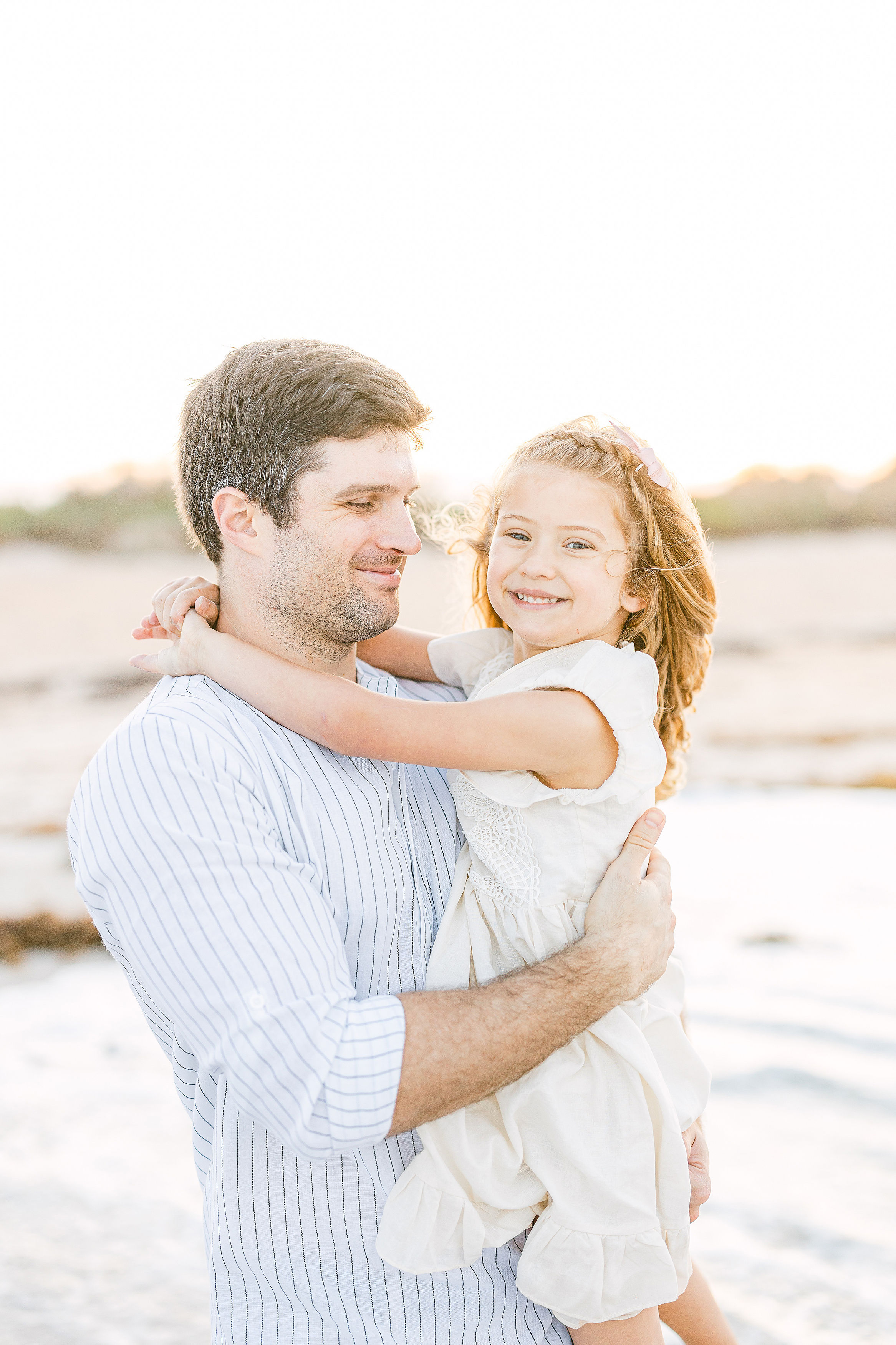 father and daughter embracing on the beach at sunset