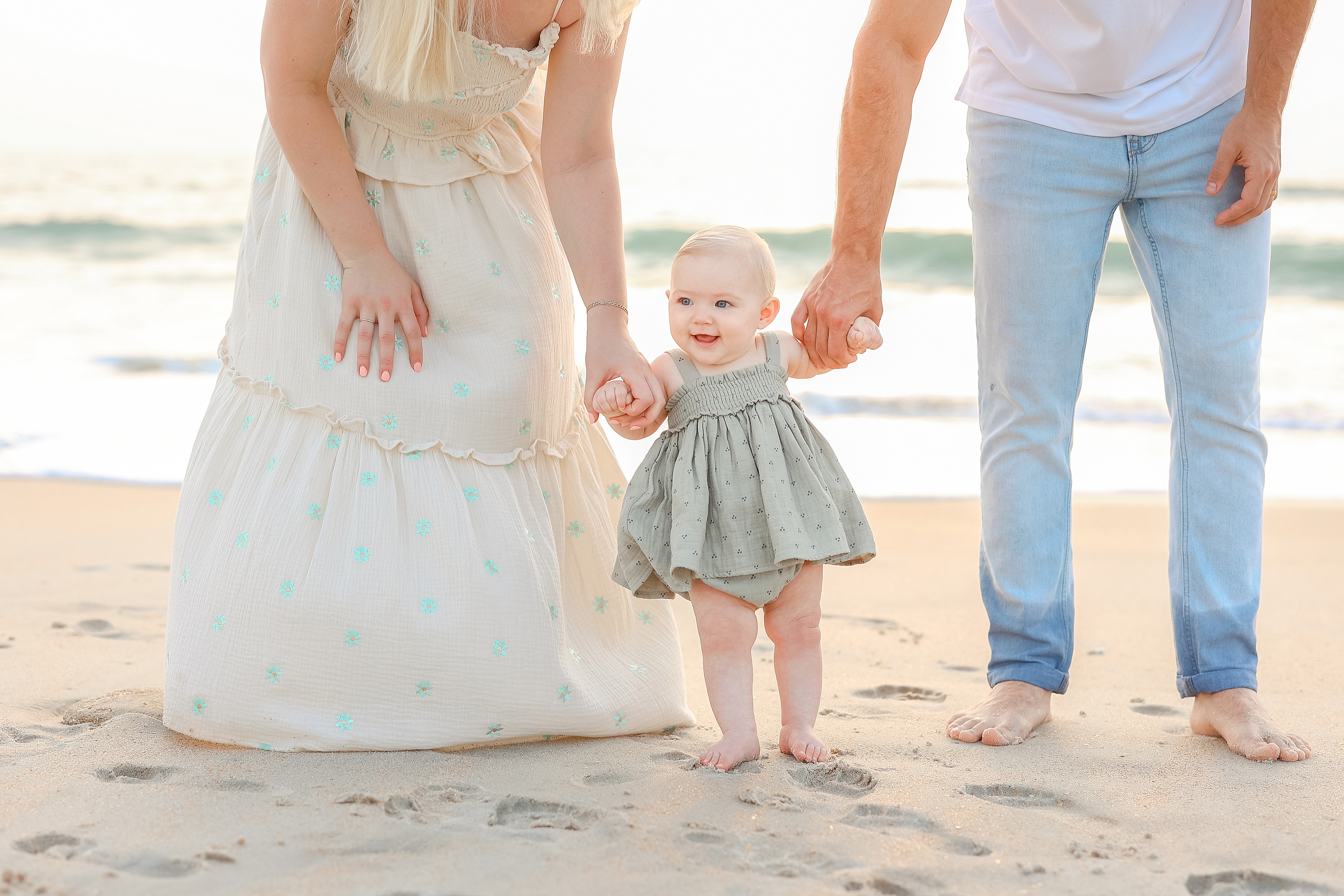 blonde woman holding baby girl at sunrise on the beach