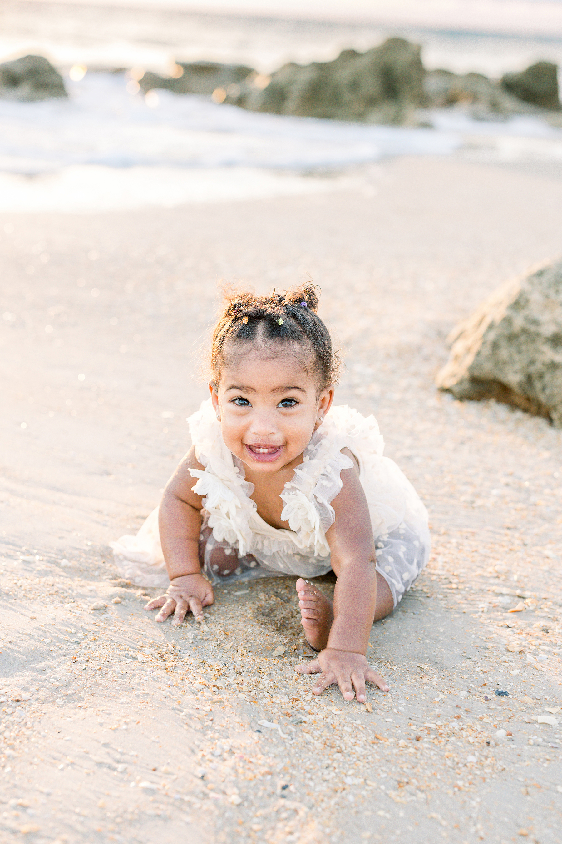 Light and airy beach portrait of a baby in neutral tulle dress.