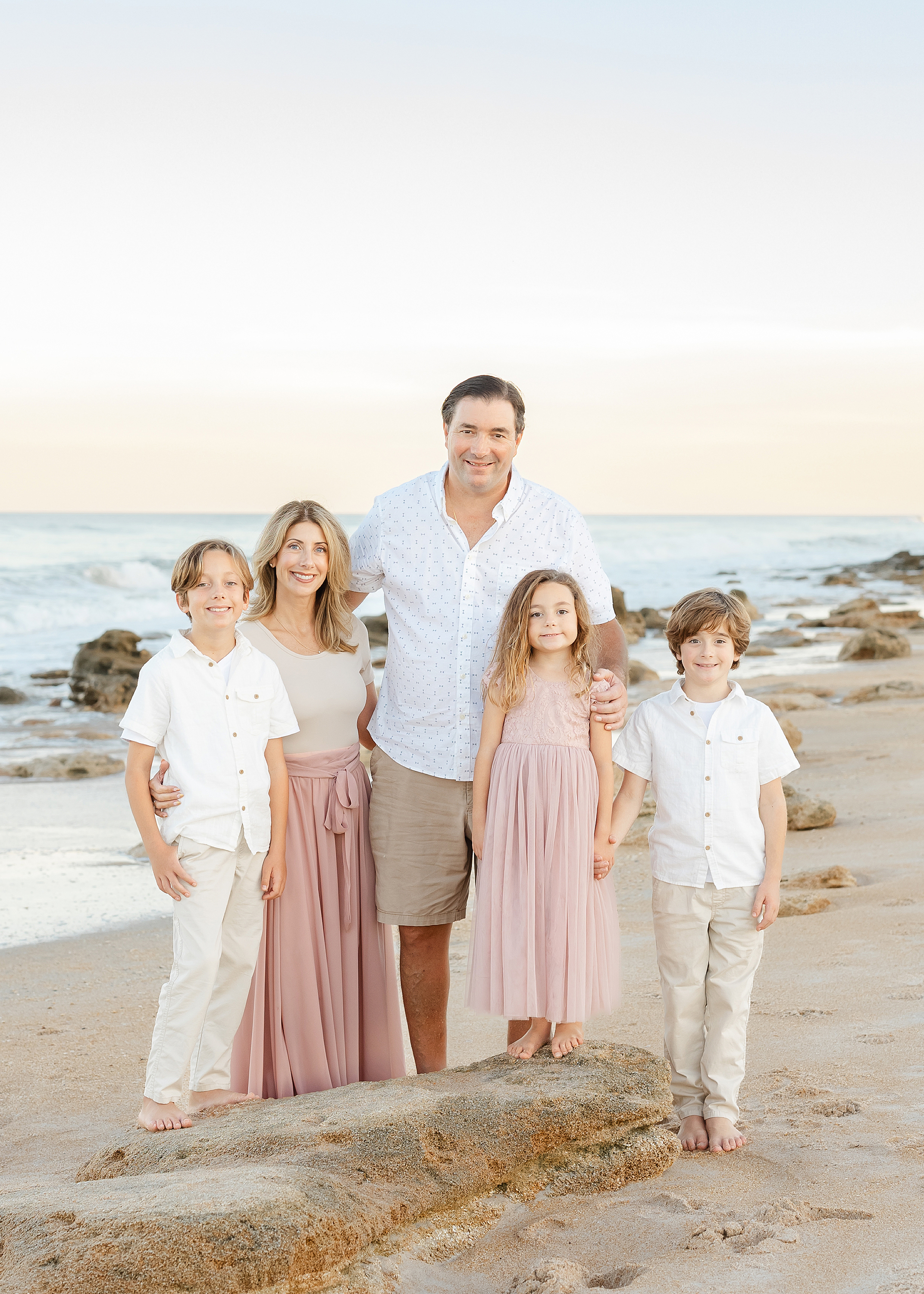 A pastel light and airy family beach portrait at sunset.