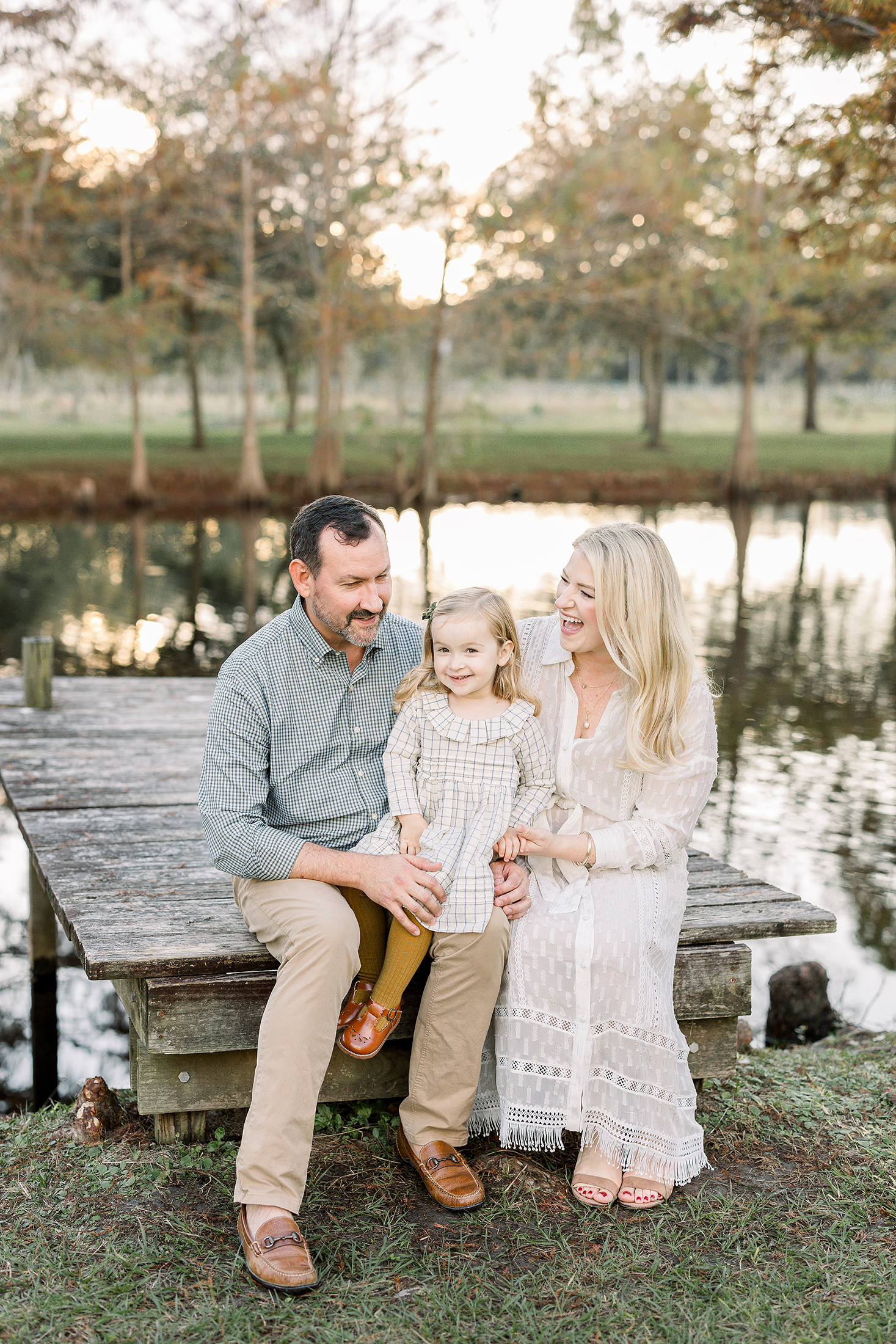 A family of three sits on the dock at Congaree and Penn farm during their fall mini portraits.