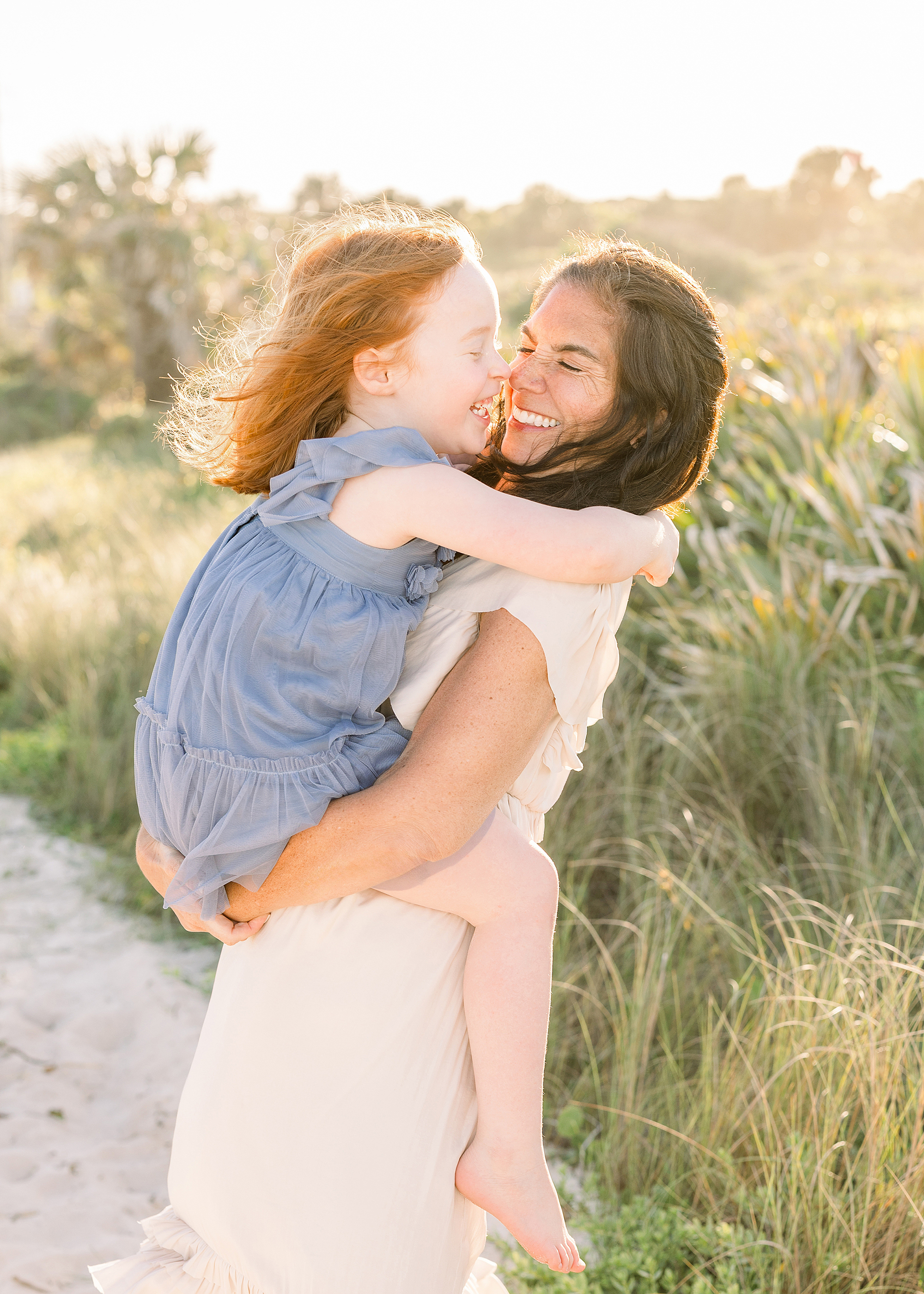 A motherhood portrait of a woman with her red haired daughter at sunset on the beach.