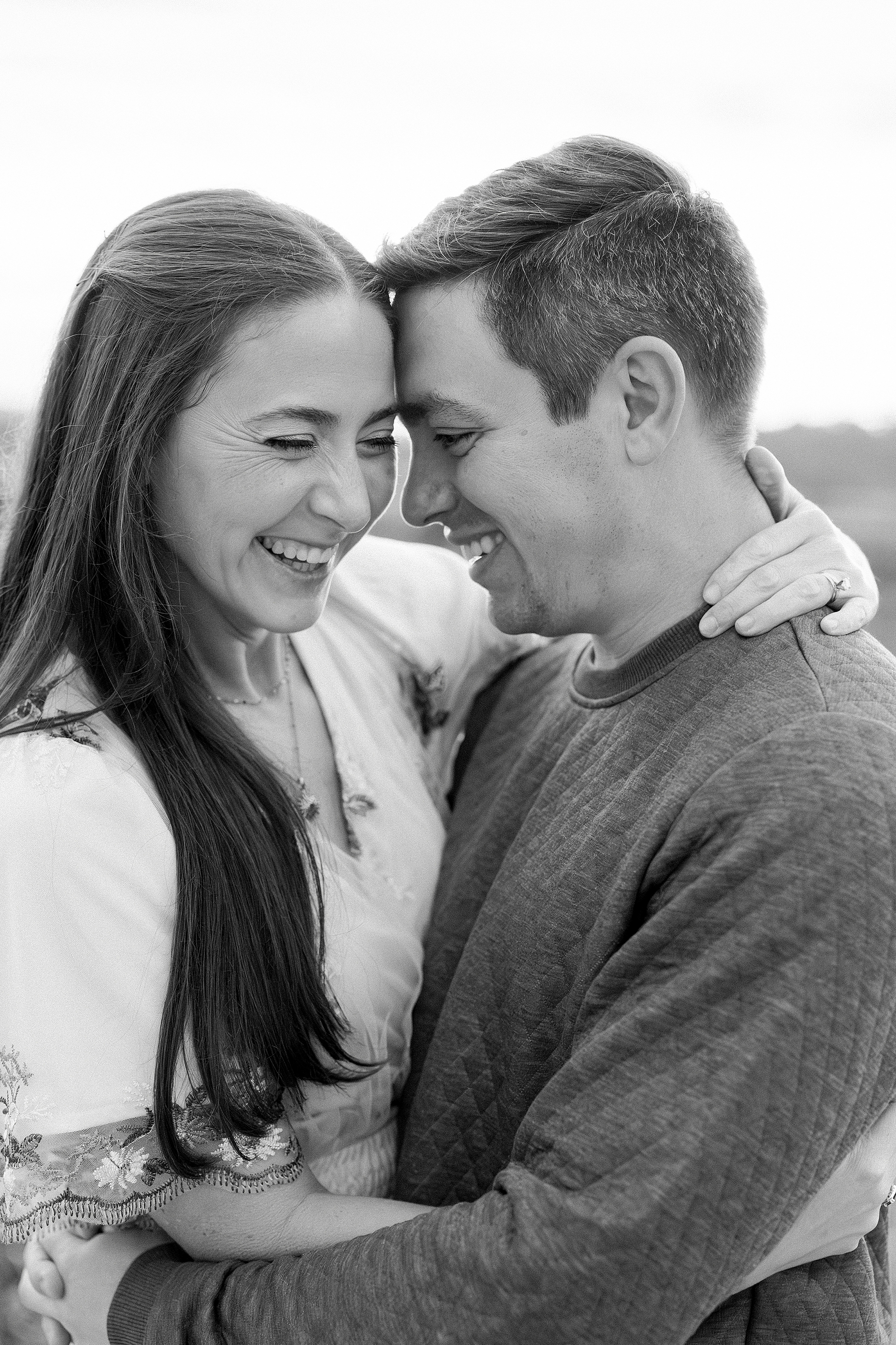 A black and white portrait of a man and woman embracing each other and laughing.