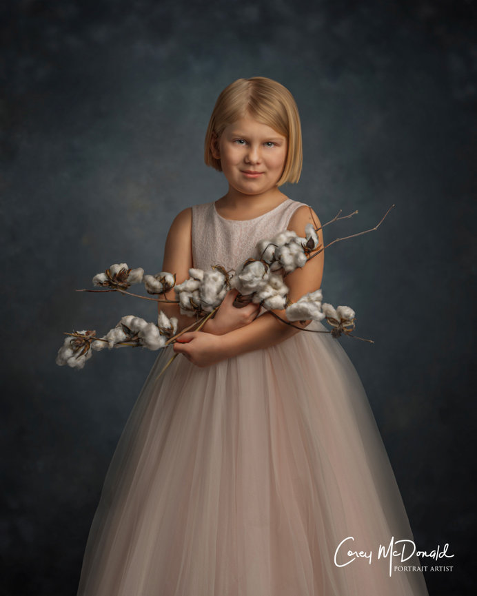 A young girl in a pink dress holds cotton branches, set against a dark, textured background.
