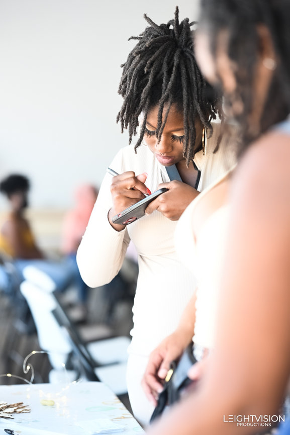 A woman with dreadlocks types on her cell phone, illustrating her connection to communication in a modern setting.