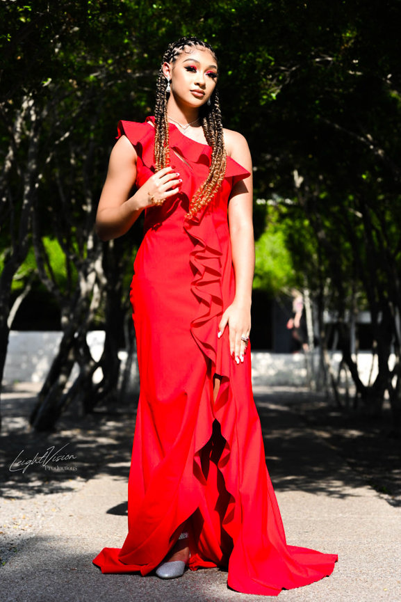A woman poses for a photo, wearing a vibrant red dress that presenting her style and grace.