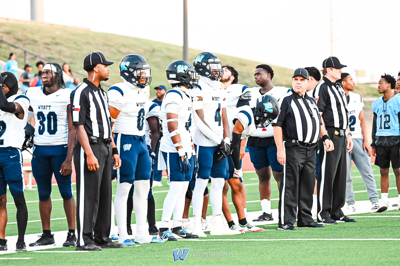 A group of football players stands together on the field, showcasing teamwork and athleticism in a vibrant setting.