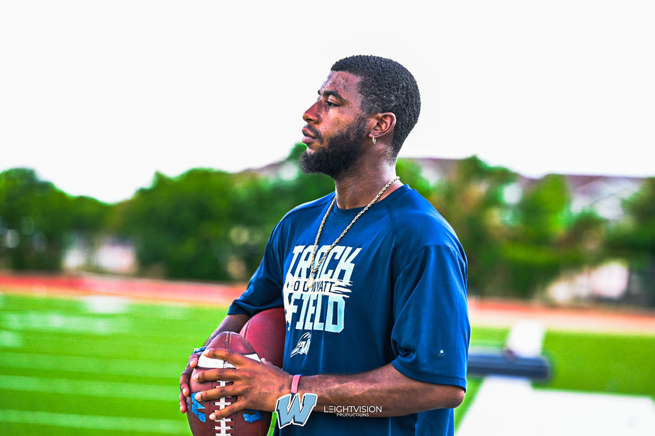 A man dressed in a blue shirt is gripping a football, poised for action on the field.