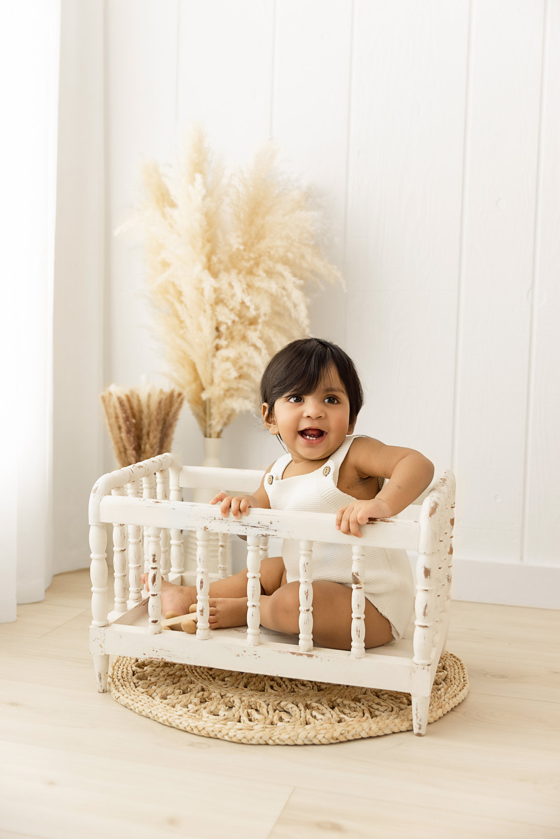 Baby sitting in a white crib in the studio lifestyle area