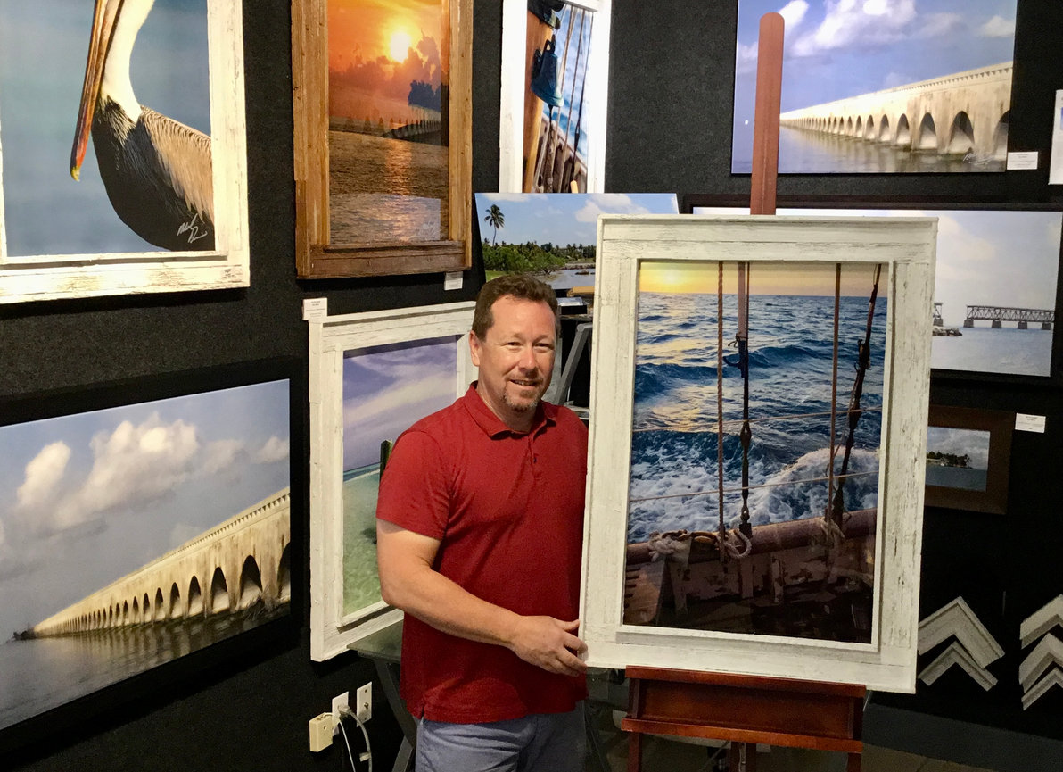 Photographer holding a framed coastal landscape artwork