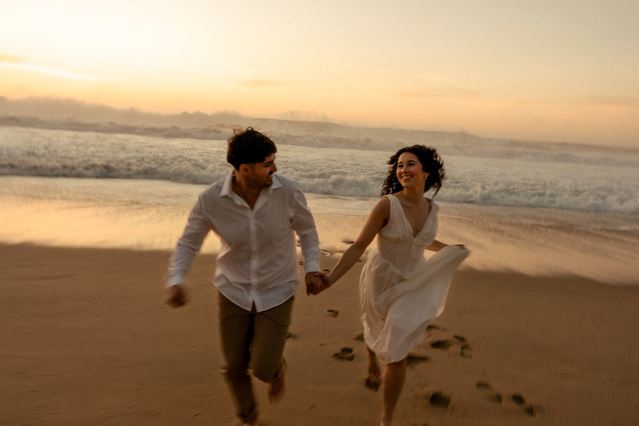 Couple running hand in hand on the beach at sunset