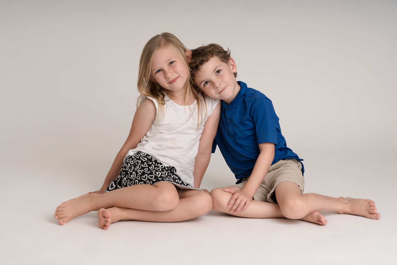 Young boy and girl siblings sitting on the studio floor in minimalist style, Iowa City, Coralville