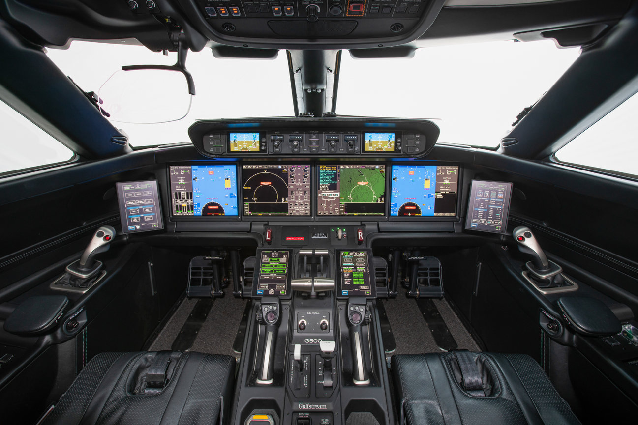 Cockpit of a modern aircraft featuring multiple digital screens and control panels.