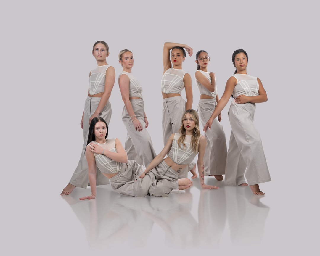 Six women posing in coordinated white outfits against a light gray studio background