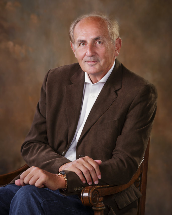 Gentleman in brown jacket sitting in an armed chair