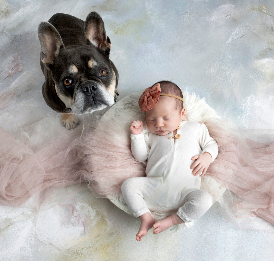 Baby lying next to a dog on a pastel background