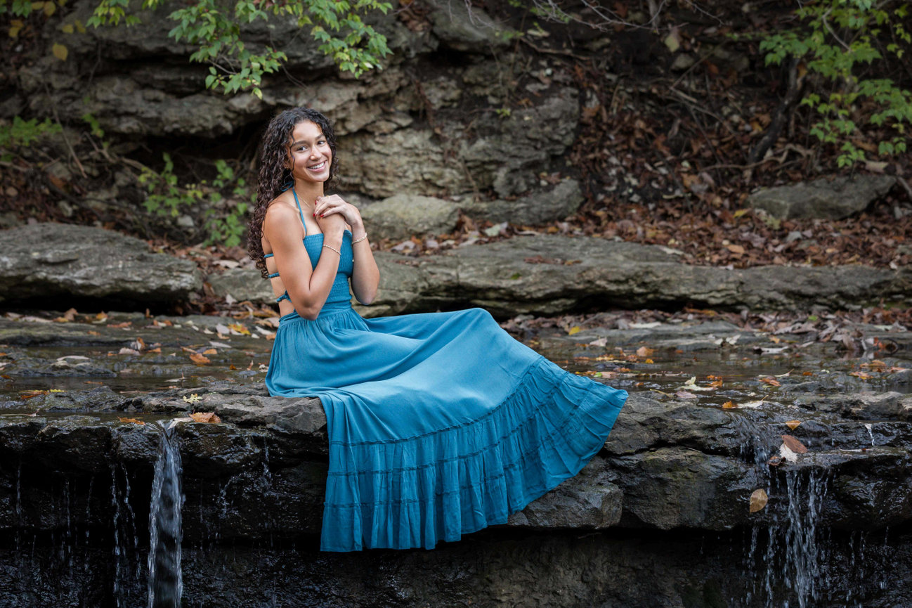 Woman sitting on a rock by a small waterfall