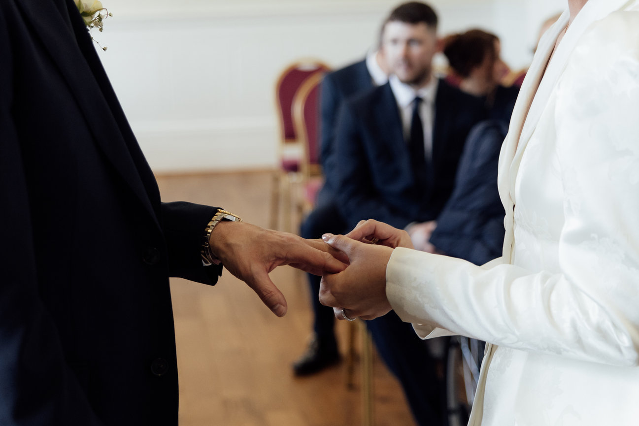 Intimate wedding photography St George's Hall Liverpool: Bride and groom exchange rings during a wedding ceremony in a hall.