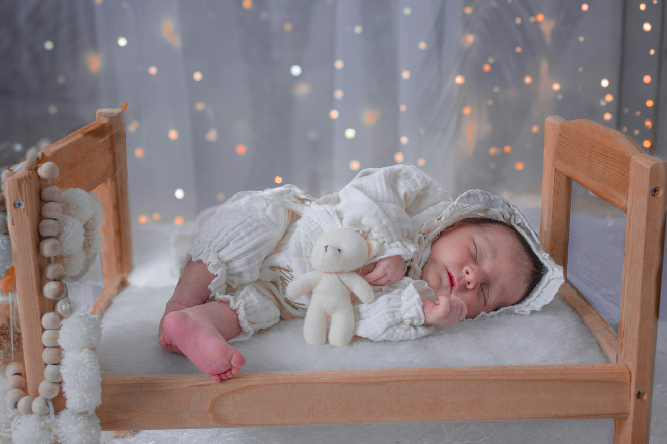 Sleeping baby in a wooden crib with warm fairy lights