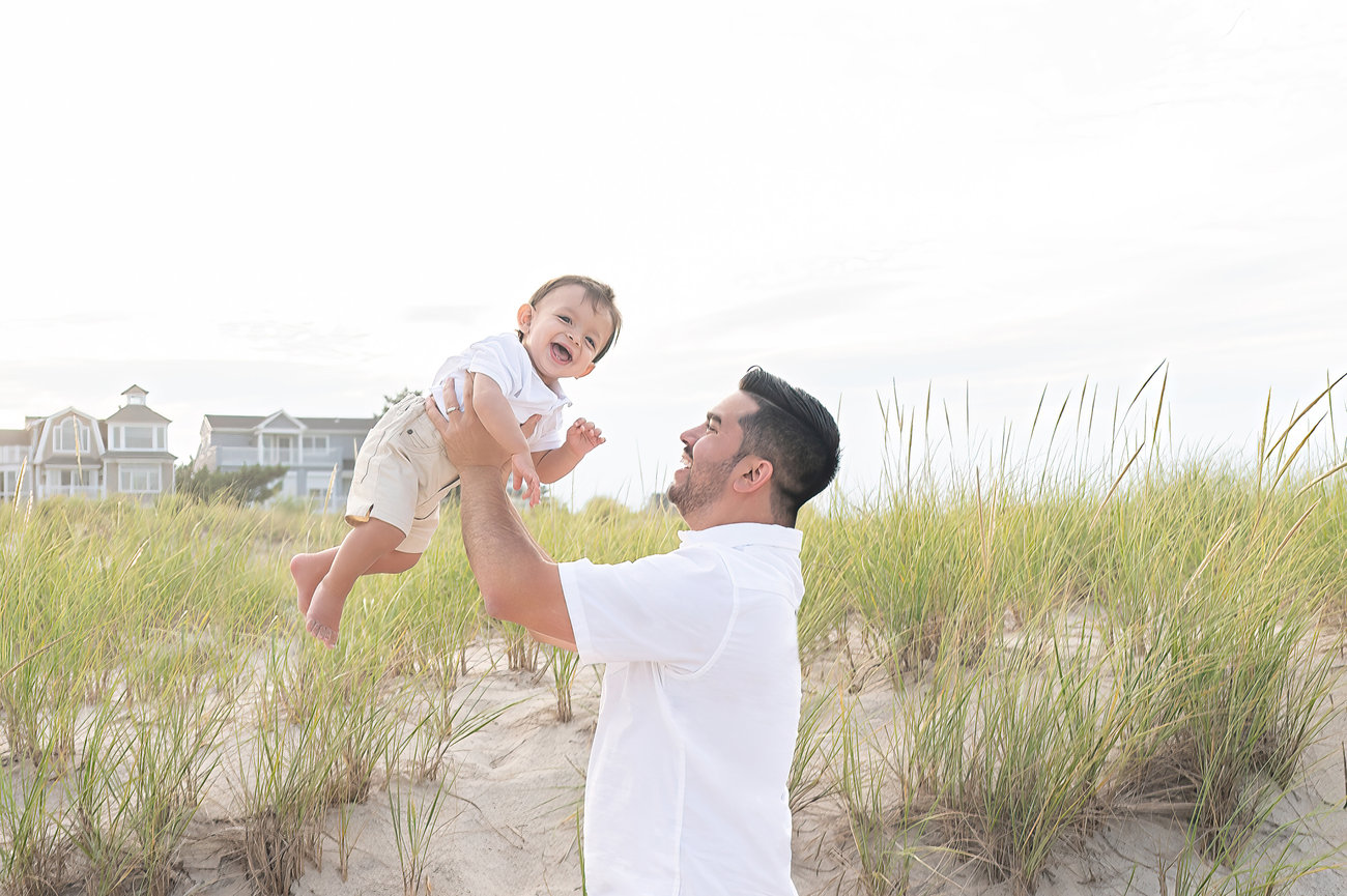 Dad lifting baby high against the backdrop of the ocean