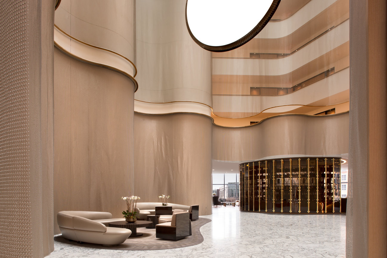 Conrad DC Lobby with Hanging Metal Screens on walls with a large round light fixture and modern marble floors.